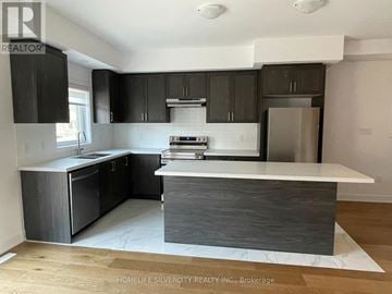Barrie townhouse for rent - A kitchen with a white counter top and black cabinets.