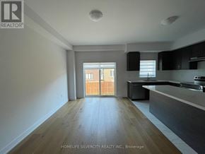 Barrie townhouse for rent - A spacious kitchen with a dining area and a view of a wooden fence.