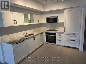 Toronto (Englemount-Lawrence) condo for rent - A kitchen with white cabinets and a granite countertop.