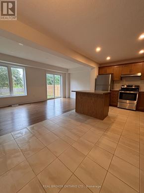 Grey Highlands townhouse for rent - A spacious kitchen with a stainless steel refrigerator and oven, and a dining area with a table and chairs.
