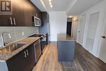 Oakville (Jm Joshua Meadows) condo for rent - A kitchen with dark brown cabinets and a stainless steel sink.