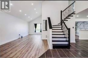 Caledonia apartment for rent - A spacious room with a wooden floor and a staircase with black railings.