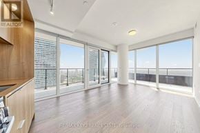 Mississauga (City Centre) condo for rent - A spacious room with wooden floors and large windows overlooking a cityscape.