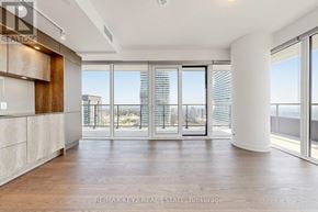 Mississauga (City Centre) condo for rent - A spacious room with wooden floors and large windows overlooking a cityscape.