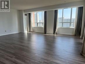 Mississauga (City Centre) condo for rent - A spacious room with wooden flooring and large windows.