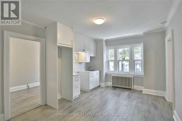 Toronto (Dufferin Grove) multi-family for rent - A spacious, empty room with a window and a radiator.