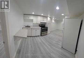 Toronto (West Hill) apartment for rent - A spacious kitchen with white cabinets and a grey floor.
