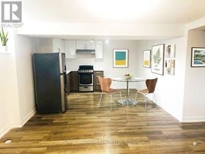 Toronto (Downsview-Roding-Cfb) apartment for rent - A kitchen with a black fridge, a white table and chairs, and a white wall.