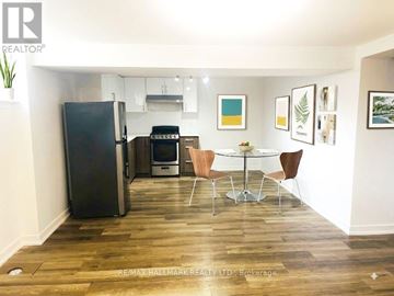 Toronto (Downsview-Roding-Cfb) apartment for rent - A kitchen with a black fridge, a white table and chairs, and a white wall.