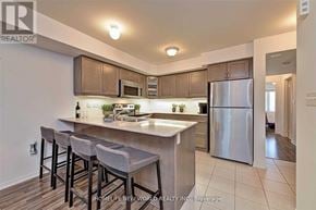 Oakville (Ro River Oaks) townhouse for rent - A modern kitchen with a bar stool and a refrigerator.