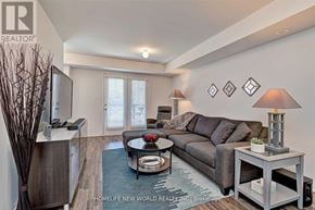 Oakville (Ro River Oaks) townhouse for rent - A living room with a grey couch, a black coffee table, and a wooden cabinet.