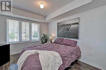 Oakville (Ro River Oaks) townhouse for rent - A bedroom with a bed covered in a purple comforter and a framed picture hanging on the wall.