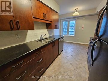 Mississauga (Cooksville) townhouse for rent - A kitchen with brown cabinets and a black refrigerator.