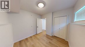Grande Prairie apartment for rent - A room with wooden floors and white walls, with a door on the left and a window on the right.