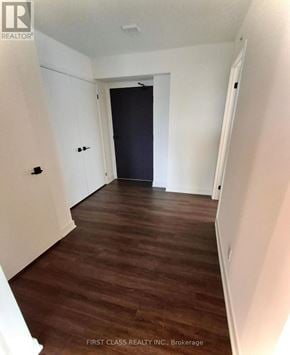 Toronto (North St. James Town) condo for rent - A room with wooden floors and white walls, with a black door at the end.