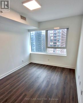 Toronto (North St. James Town) condo for rent - A room with wooden flooring and a window showing a building outside.