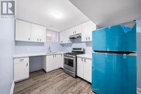 Brampton (Sandringham-Wellington) apartment for rent - A kitchen with white cabinets and a blue fridge.