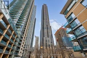 Toronto (Annex) condo for rent - A tall building stands in the middle of a cityscape with other buildings around it.