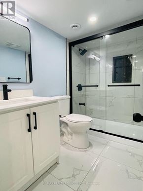 Brampton (Westgate) apartment for rent - A white toilet sits in a bathroom with a white sink and a glass shower door.