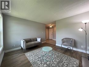 Windsor condo for rent - A living room with a grey couch, a chair, and a round table.