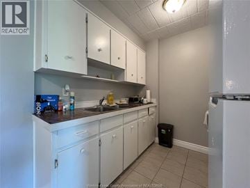 Windsor condo for rent - A kitchen with white cabinets and a black trash can.