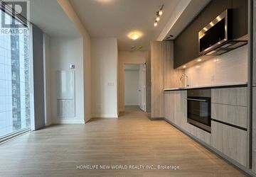 Toronto (Waterfront Communities) condo for rent - A modern kitchen with wooden floors and a large window.