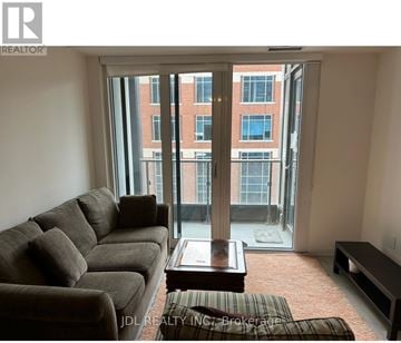 Toronto (Waterfront Communities) condo for rent - A living room with a couch, coffee table, and a view of a building through the window.