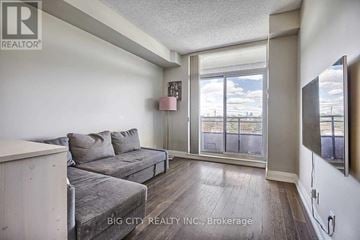 Toronto (York University Heights) condo for rent - A living room with a grey couch and a large window.