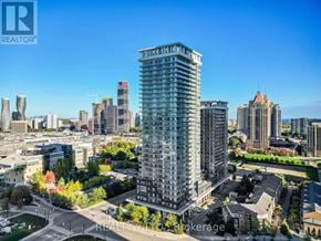 Mississauga (City Centre) condo for rent - A tall building with many windows is the focal point of a cityscape.