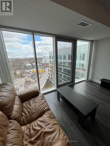 Kingston (Central City East) condo for rent - A brown leather sofa sits in a living room with a view of the city.