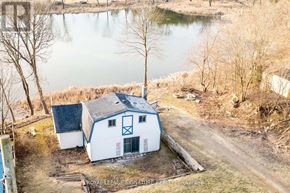 Whitchurch-Stouffville apartment for rent - A white barn with a blue stripe is situated by a body of water.