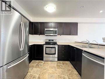 Kitchener townhouse for rent - A kitchen with black cabinets and a stainless steel refrigerator.