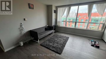 Toronto (Annex) condo for rent - A living room with a grey sofa and a black rug.