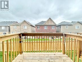 Oshawa (Windfields) townhouse for rent - A wooden deck with a railing in the foreground and houses in the background.