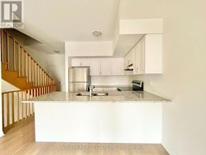Oshawa (Windfields) townhouse for rent - A kitchen with white cabinets and a granite countertop.