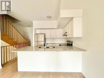 Oshawa (Windfields) townhouse for rent - A kitchen with white cabinets and a granite countertop.