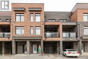 Pickering (Village East) townhouse for rent - A white car is parked in front of a brick building.