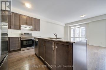 Ajax (South East) townhouse for rent - A modern kitchen with wooden cabinets and stainless steel appliances.