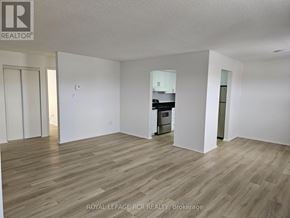 Aurora (Hills Of St Andrew) apartment for rent - A spacious room with wooden flooring and white walls, with a kitchen visible in the background.