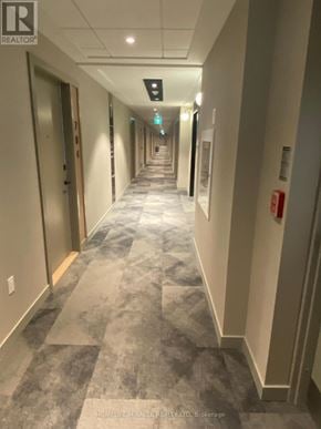 Milton (Cb Cobban) condo for rent - A long hallway with doors on both sides and a fire extinguisher on the right wall.