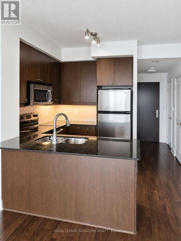 Mississauga (City Centre) condo for rent - A modern kitchen with dark wood cabinets and stainless steel appliances.