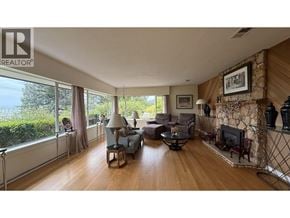 West Vancouver apartment for rent - A living room with a stone fireplace and a large window.