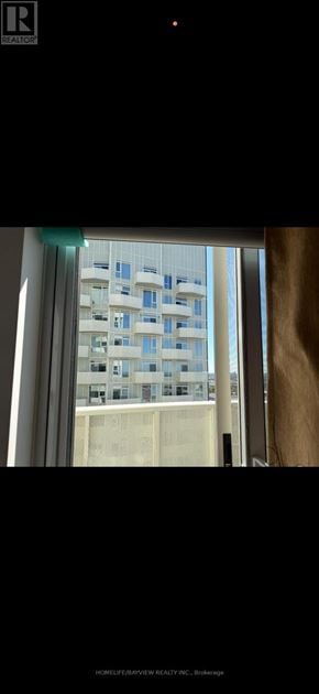Vaughan (Concord) condo for rent - A tall building with many windows is visible through a window.