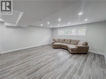 Kitchener apartment for rent - A spacious living room with a large sectional sofa and hardwood flooring.