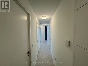 Oakville (Go Glenorchy) condo for rent - A long hallway with a door on the left and a window on the right.