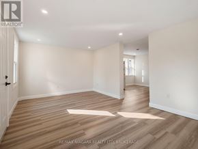 Fort Erie (Central) triplex for rent - A spacious room with wooden flooring and white walls.