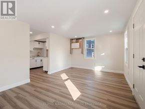 Fort Erie (Central) triplex for rent - A spacious room with wooden flooring and white walls.