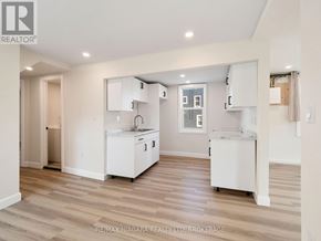 Fort Erie (Central) triplex for rent - A kitchen with white cabinets and a wooden floor.