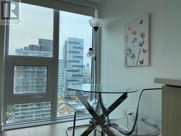 Toronto (Bay Street Corridor) condo for rent - A modern living room with a glass table and a view of the city.