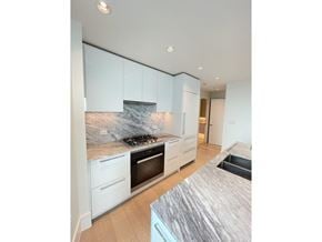 White Rock apartment for rent - A modern kitchen with a marble backsplash and white cabinets.